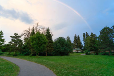 Scenic view of rainbow over trees on field against sky