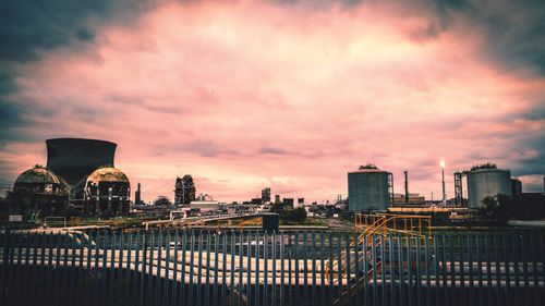 City by river against sky during sunset