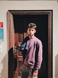 Portrait of young man standing at door