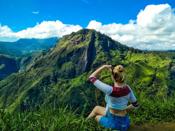 Rear view of woman looking at mountains against sky