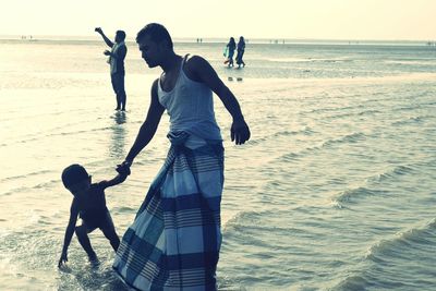 Rear view of two people standing on beach