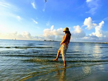 Woman standing on shore at beach against sky