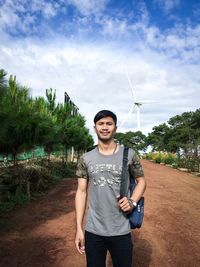 Portrait of smiling man standing on field against sky