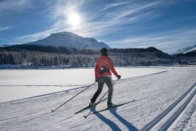 Full length of person skiing on field against snowcapped mountains against sky