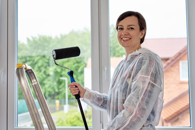 Portrait of young woman using mobile phone while standing in gym