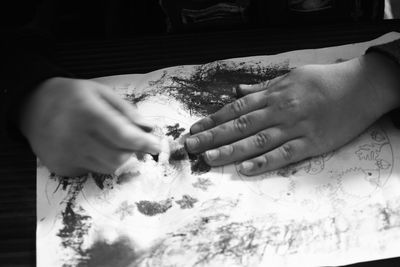 Cropped hands of child painting in paper