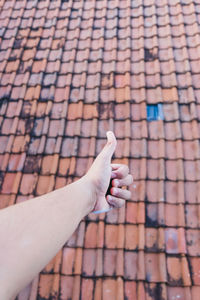 Cropped hand showing thumbs up against roof