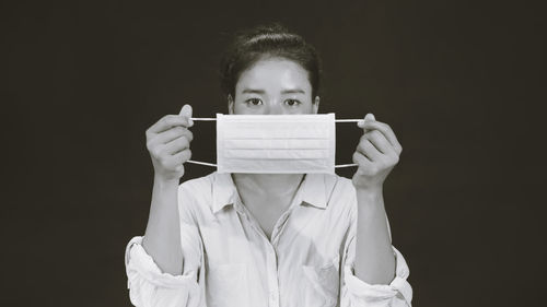 Portrait of man holding mask against black background