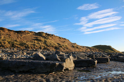 Scenic view of sea by mountain against sky