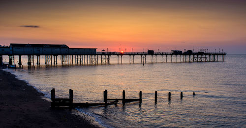 Pier over sea against sky during sunset