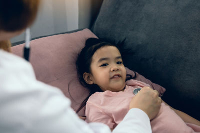 Mother and baby girl lying on bed