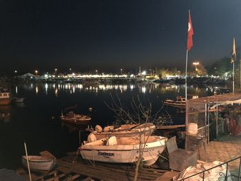 Boats moored at harbor against sky at night