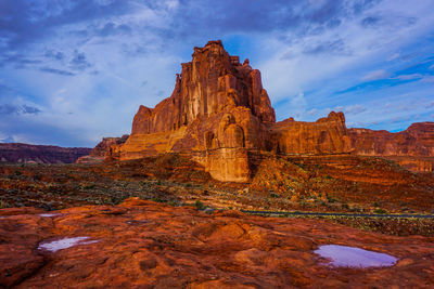 Rock formations on landscape against cloudy sky