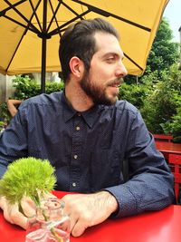 Young man looking away while sitting at table