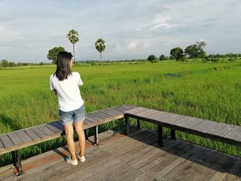 Woman standing on grass against sky