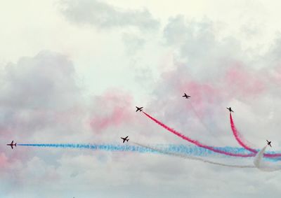 Low angle view of airplane flying against cloudy sky