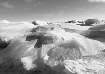 Frozen river against sky on sunny day