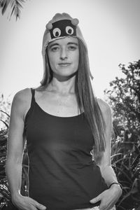 Portrait of young woman standing against trees