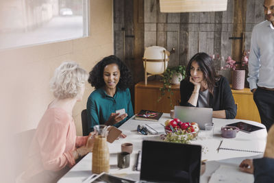 Businesswoman looking at colleagues using mobile phones during meeting in portable office truck