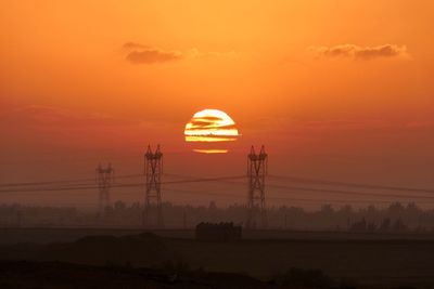 Silhouette electricity pylon against sky during sunrise