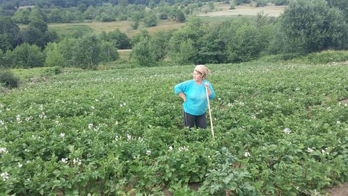 Woman with stick standing in potato farm