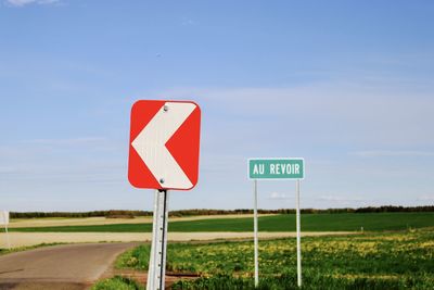 Road sign on field against sky