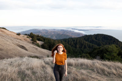 Portrait of woman walking on plants against mountains