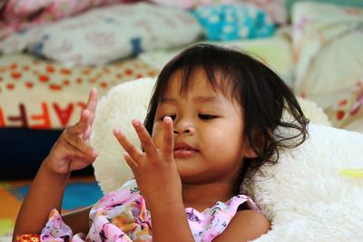 Close-up of cute girl lying on bed at home