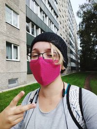 Portrait of young woman standing against building