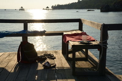 Chairs on shore against sky during sunset