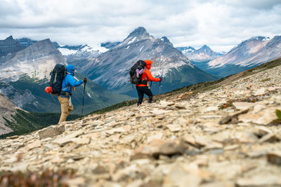 Rear view of people on snowcapped mountains against sky