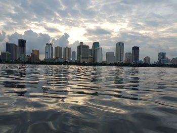 Scenic view of river by buildings against sky during sunset