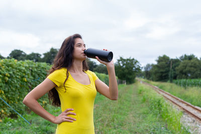 Young woman photographing with camera against sky