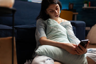 Full length of woman using phone while sitting on sofa