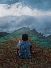 Rear view of boy sitting on land