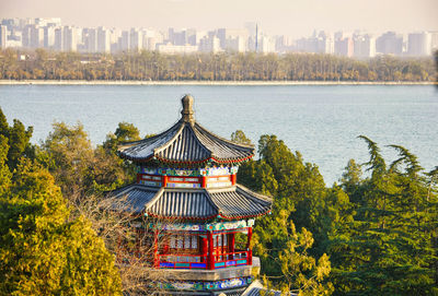 Traditional building by lake against sky in city