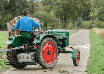 Rear view of tractor on road amidst field