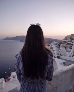 Rear view of woman looking at cityscape against clear sky