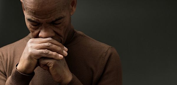 Close-up of senior man with hands against black background