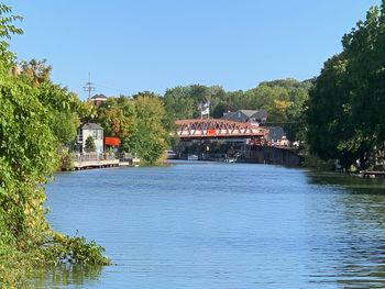 Scenic view of river by building against clear blue sky