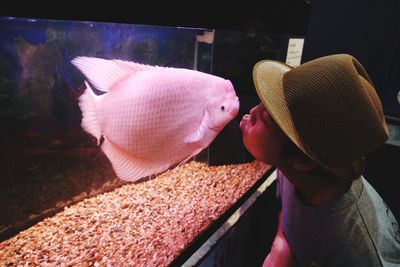 Man kissing fish in aquarium