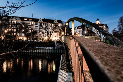 Bridge over river by buildings against sky in city