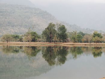 Scenic view of lake by trees against mountain in laos.