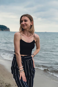 Young woman standing on blurred beachside background. attractive female enjoying walking the sea