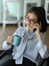 Businesswoman holding coffee cup while sitting in office