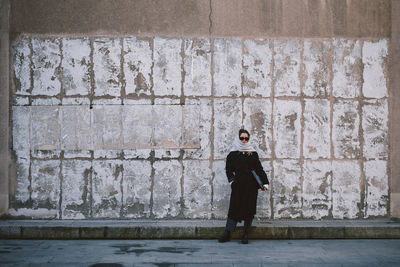 Full length of woman standing against wall outdoors
