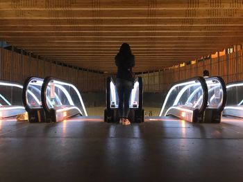 Rear view of woman in illuminated corridor