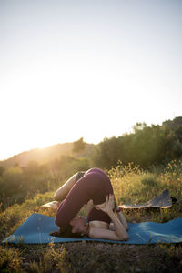 Woman relaxing on field against clear sky