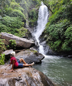 Rear view of man sitting on rock