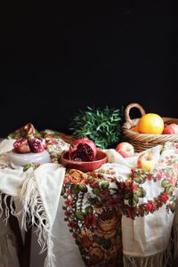 Close-up of fruits in basket on table against black background